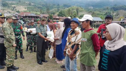 Personel TNI menyerahkan bantuan sembako kepada warga dalam pembukaan TMMD ke-125 di Enrekang, disaksikan oleh aparat dan masyarakat.