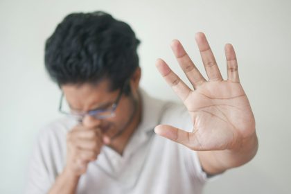 Orang batuk dengan masker, menunjukkan gejala kanker paru.